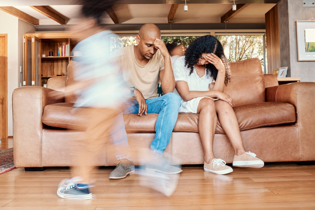 Hyperactive child running while parents are looking stressed and unable to cope