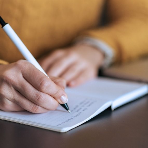 A close up of a woman writing in a notebook