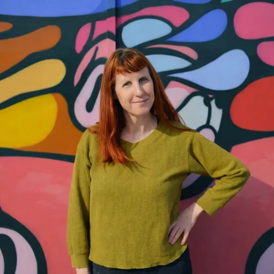 Dr Rachel Brown smiling in front o colourful mural in Bristol