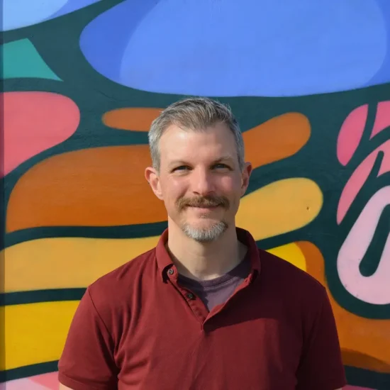 Dr Andrew Bamber smiling in front o colourful mural in Bristol